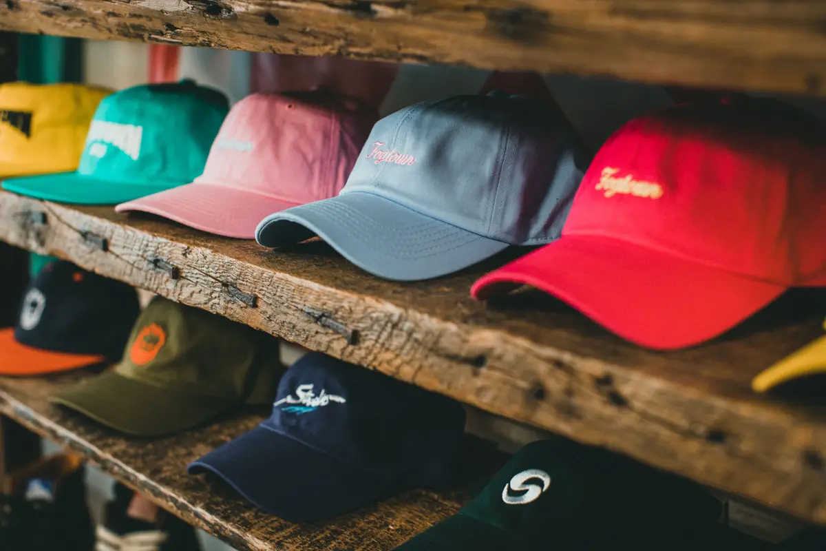 Rows of colorful embroidered baseball caps on rustic wooden shelves