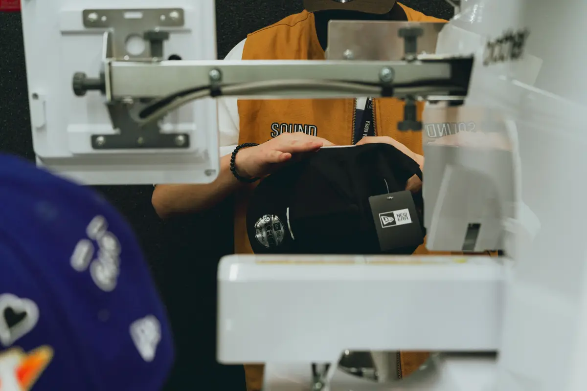 A black cap clamped into an embroidery machine in a custom hat shop