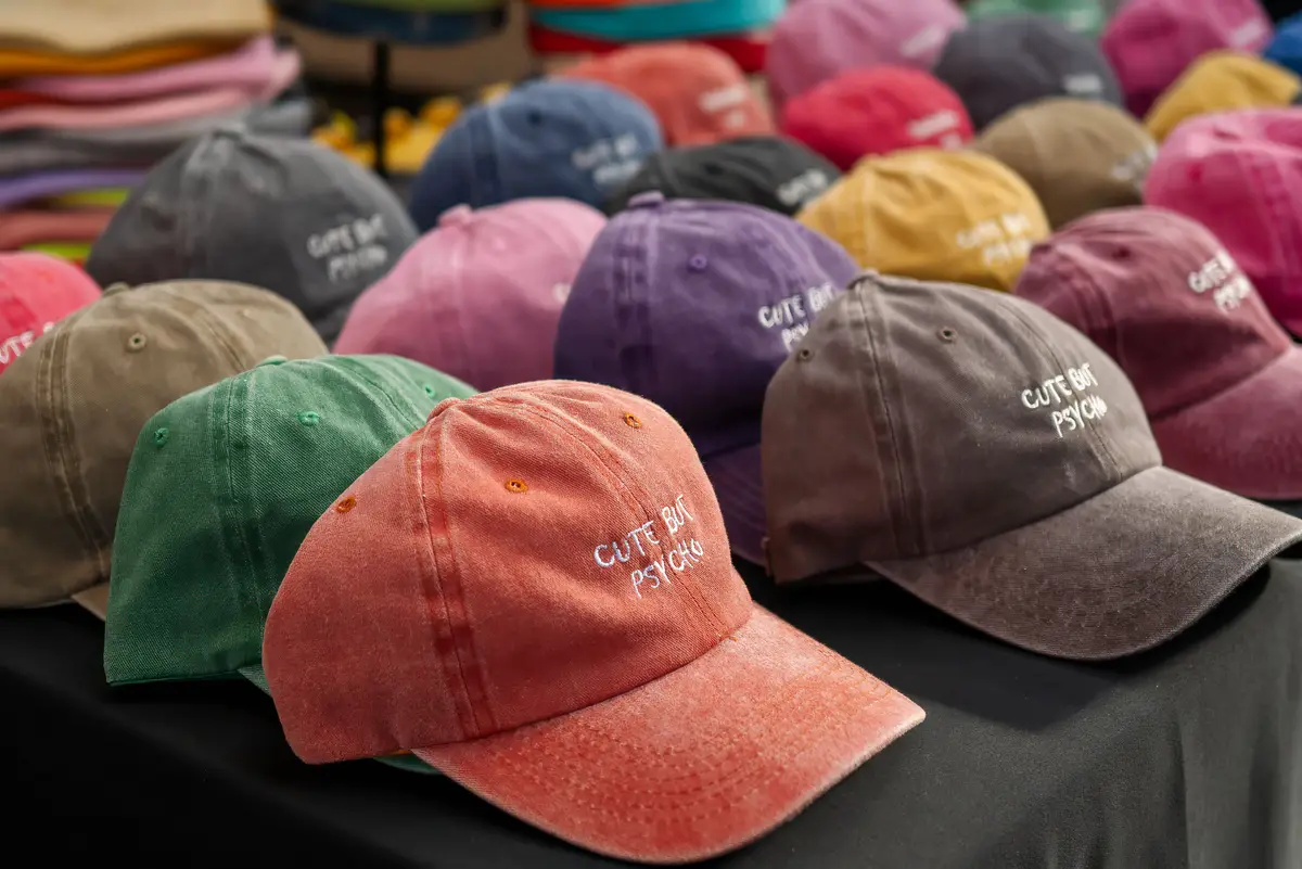 A table covered in colorful washed baseball caps with embroidered text