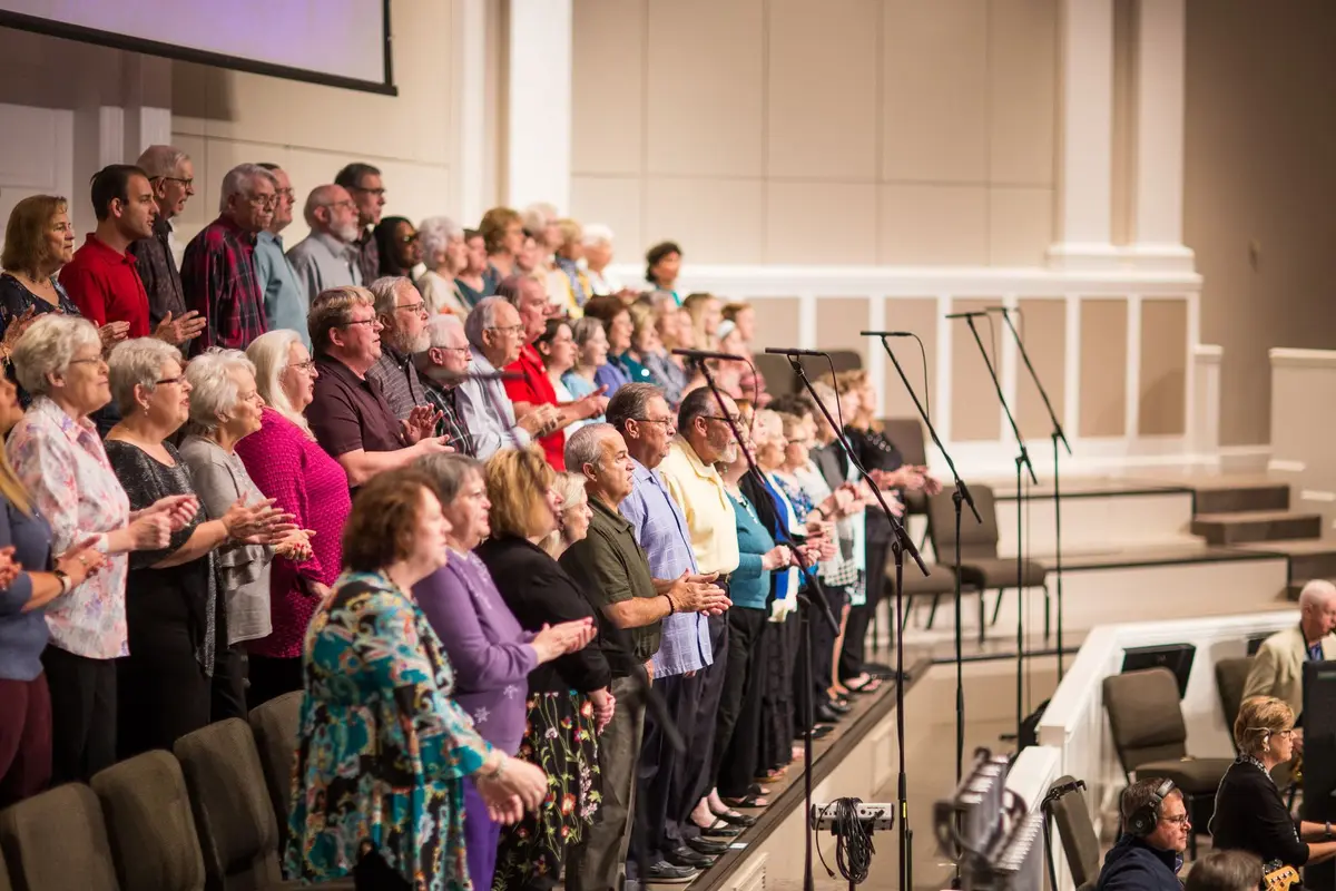 A large church choir standing and singing together in a modern sanctuary