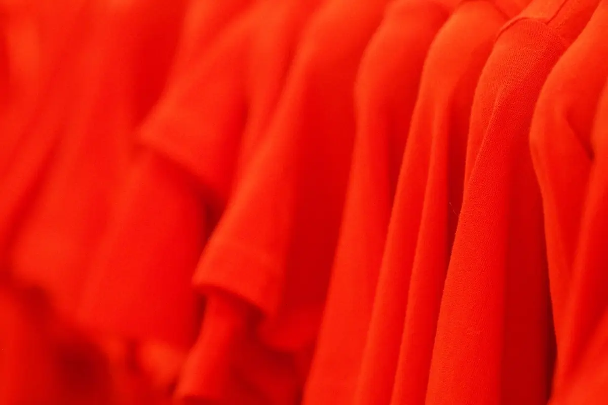 A row of bright red t-shirts hanging on a rack