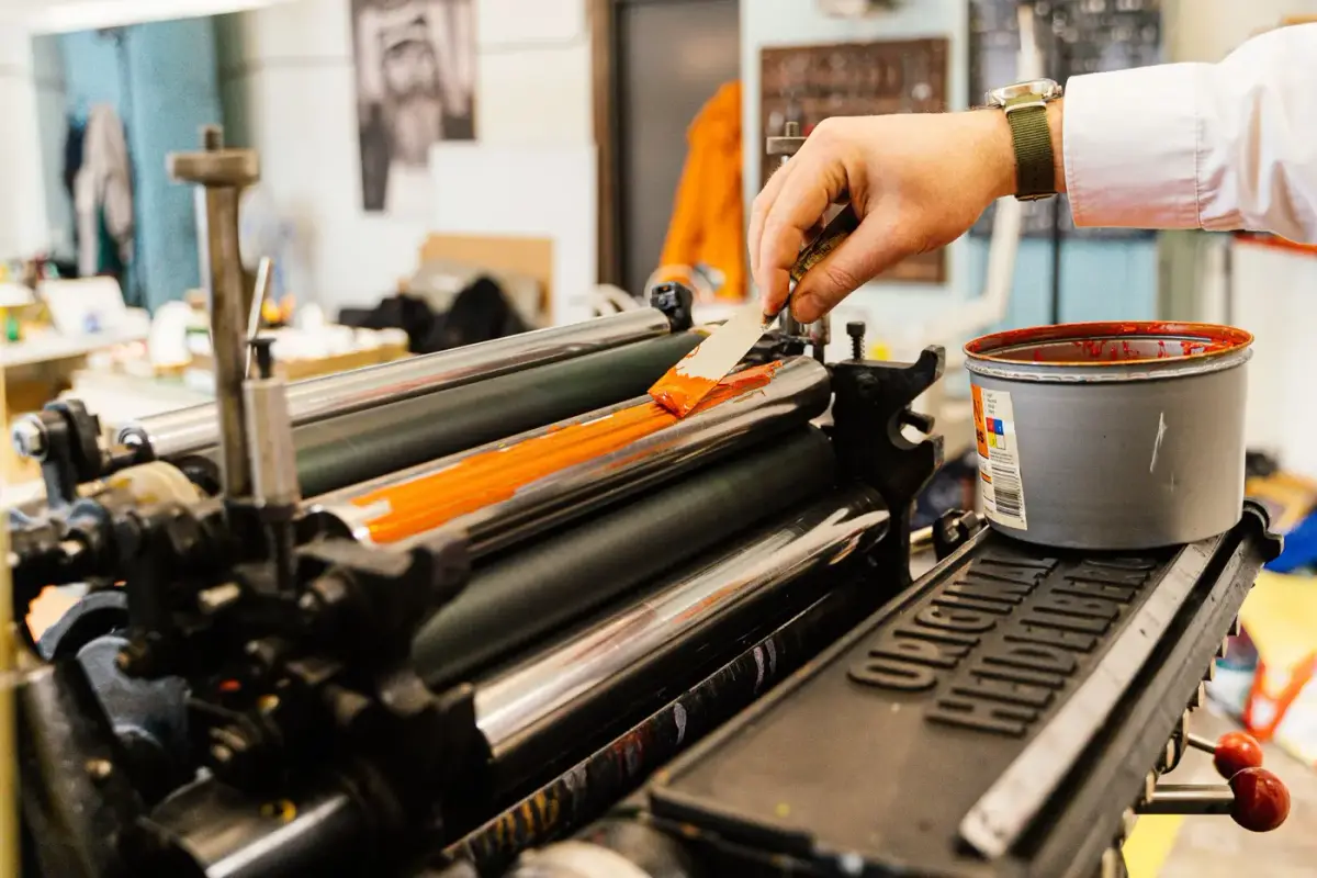 A screen printing press applying bright orange ink to apparel