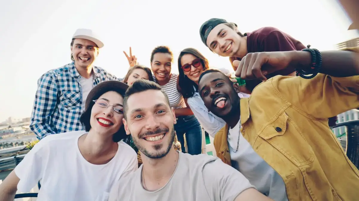 A happy group of young adults taking a group selfie outdoors