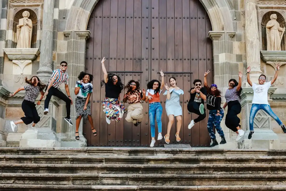 A group of young people jumping for joy on the steps outside a church