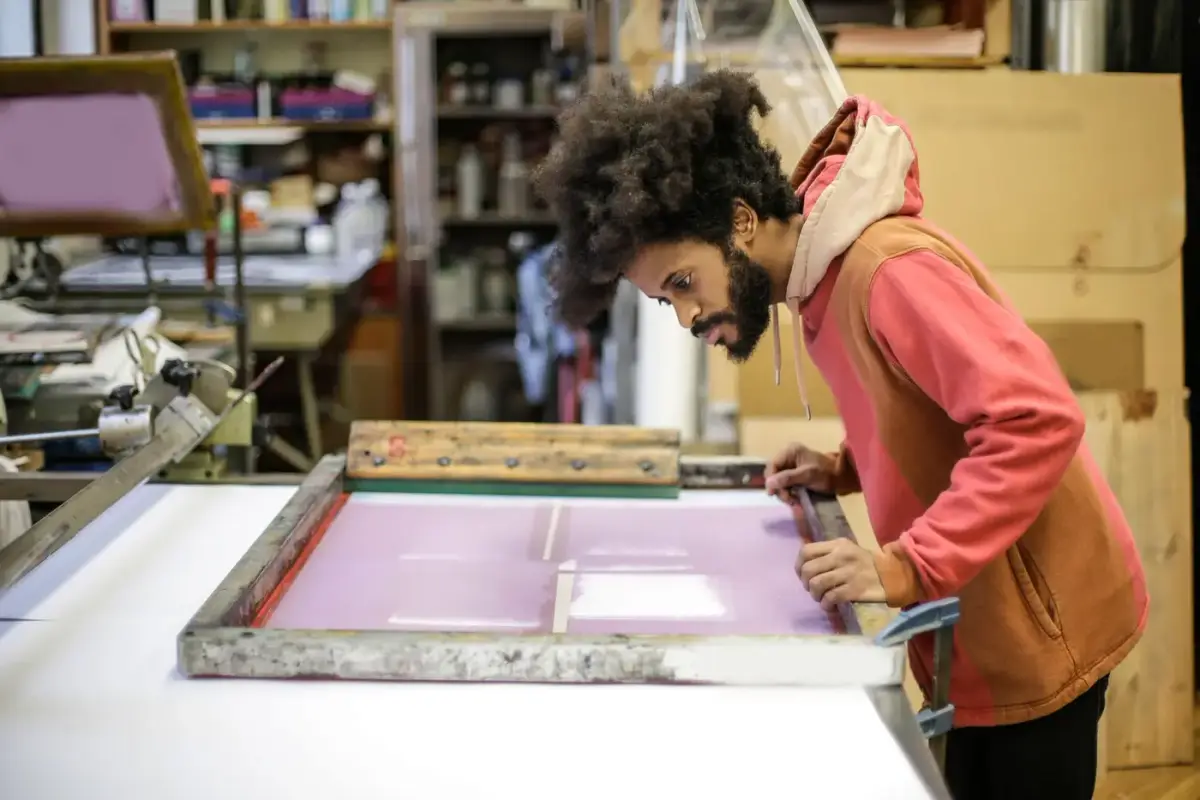 A printer preparing a screen printing frame with colored ink in a workshop