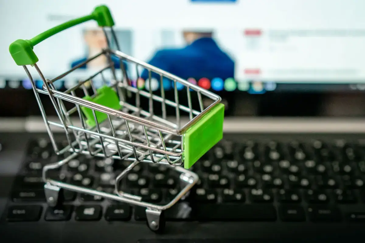 A miniature shopping cart resting on a laptop keyboard