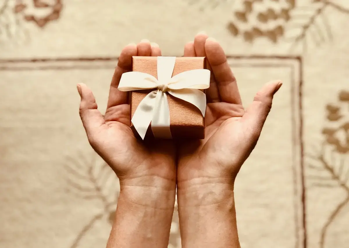 Hands presenting a small wrapped corporate gift