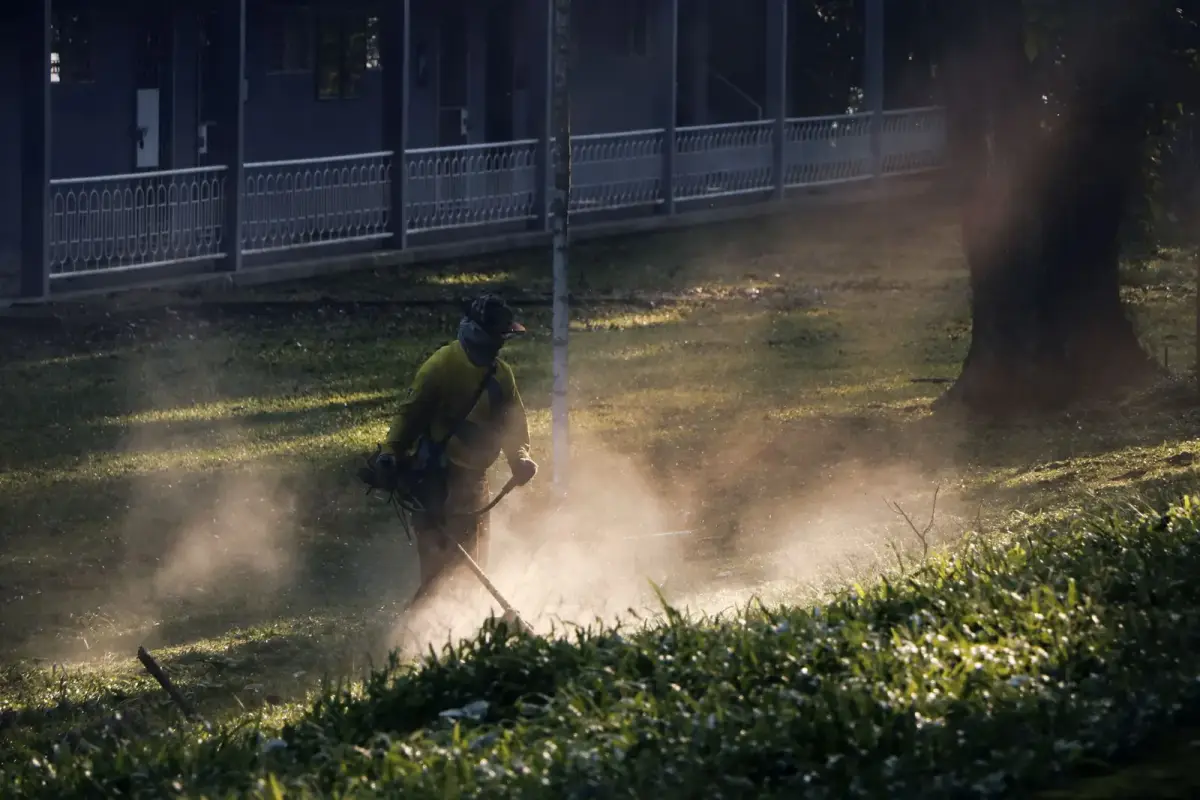 A landscaper cutting grass in a breathable work shirt