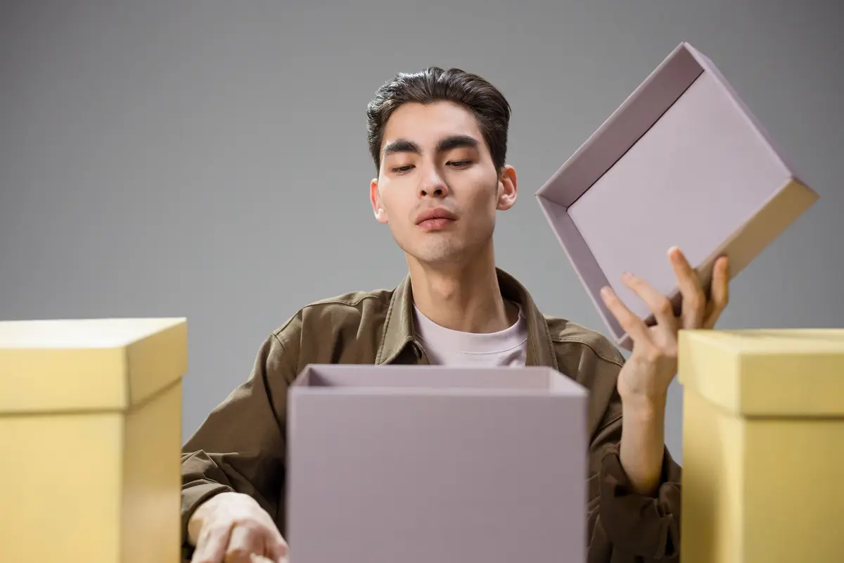 A man opening a lavender gift box with a doubtful expression