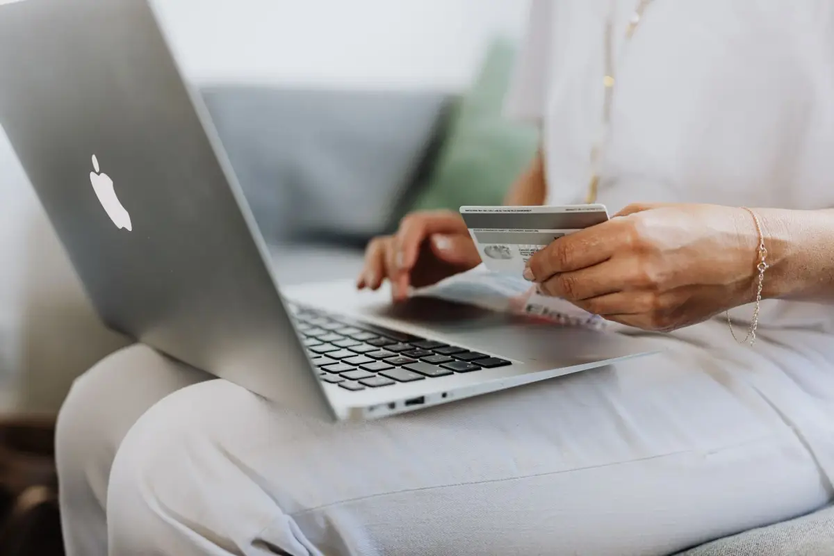 A person ordering branded apparel on a laptop with a card in hand
