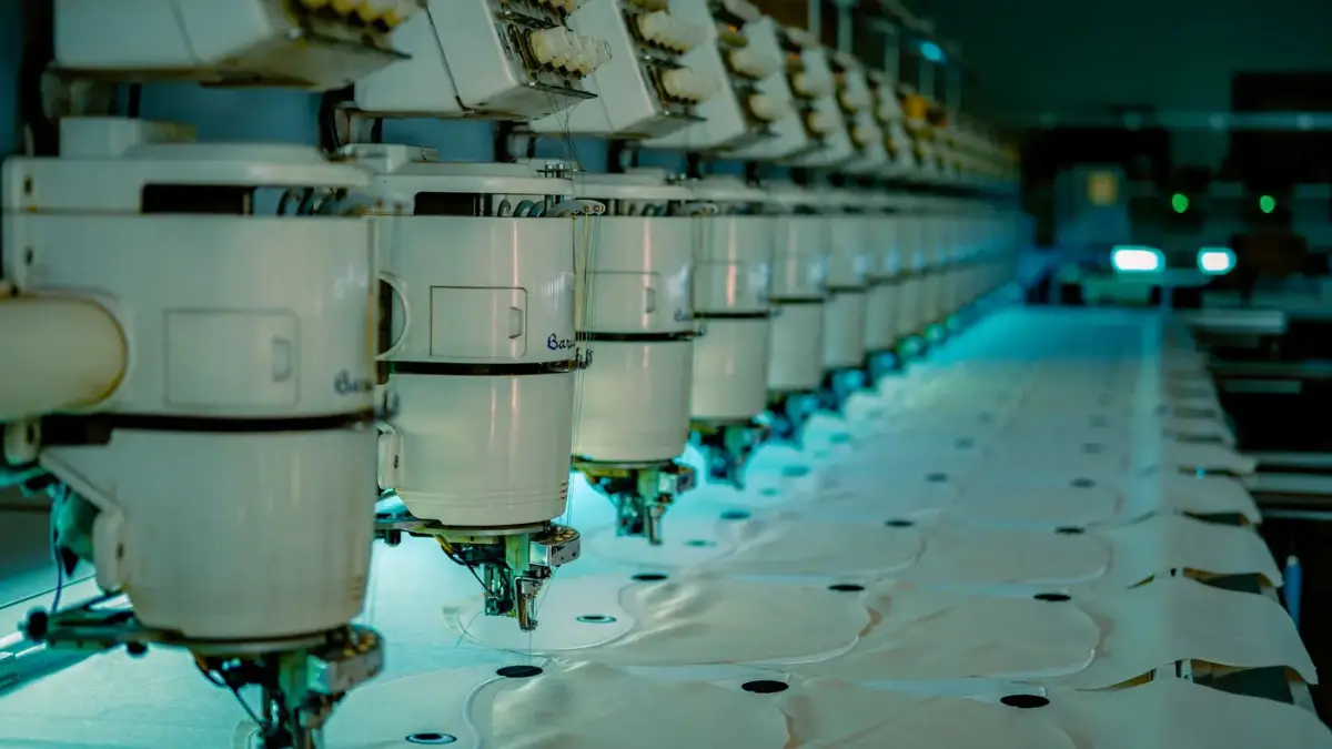 A row of industrial embroidery machines stitching in a factory