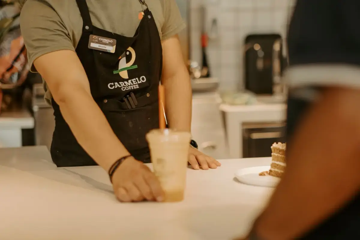 A restaurant staff member wearing a branded black apron with an embroidered logo