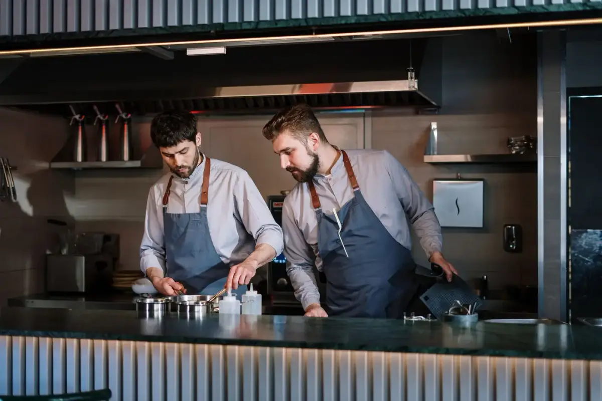 Two chefs in aprons working at a restaurant kitchen pass