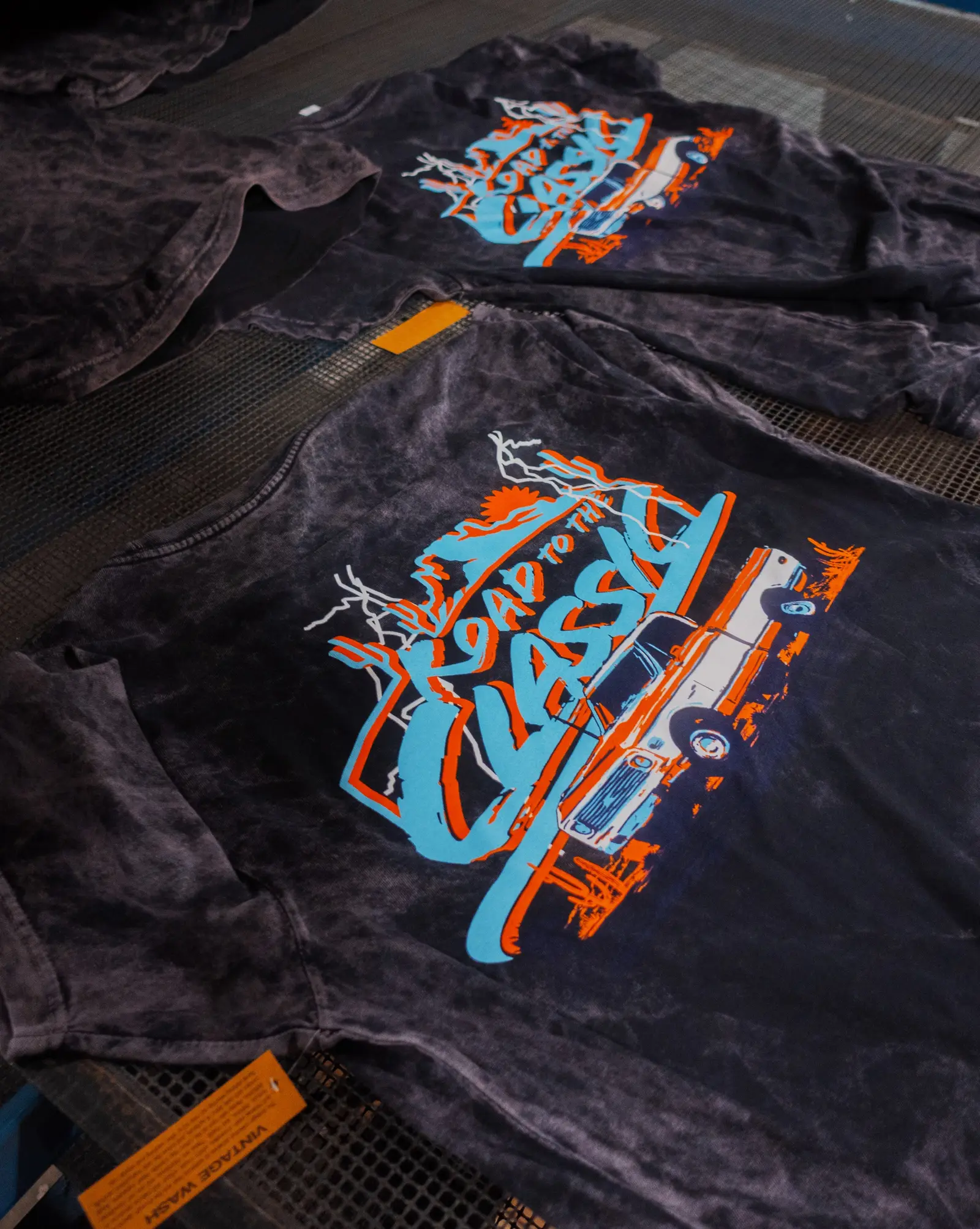 Screen printed t-shirts in a vintage wash with a multi-color design, fresh off the press