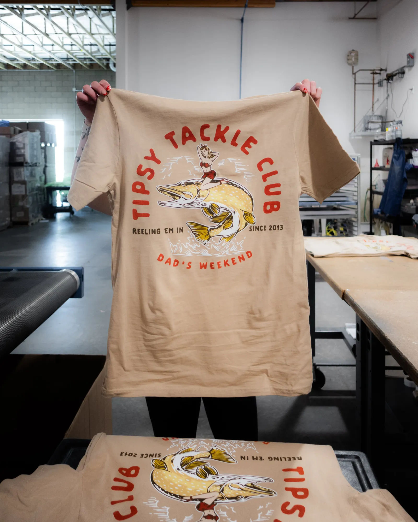 A finished custom screen-printed t-shirt held up in the shop